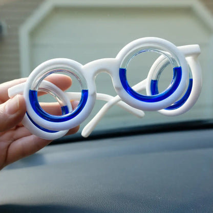 White motion sickness glasses, folded and held by hands inside a car, emphasizing convenience and portability for travel comfort.